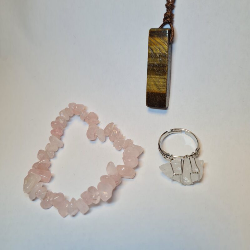 Set mit Rosenquarz Armband, Tigerauge Anhänger und weißem Quarz Ring auf weißem Hintergrund