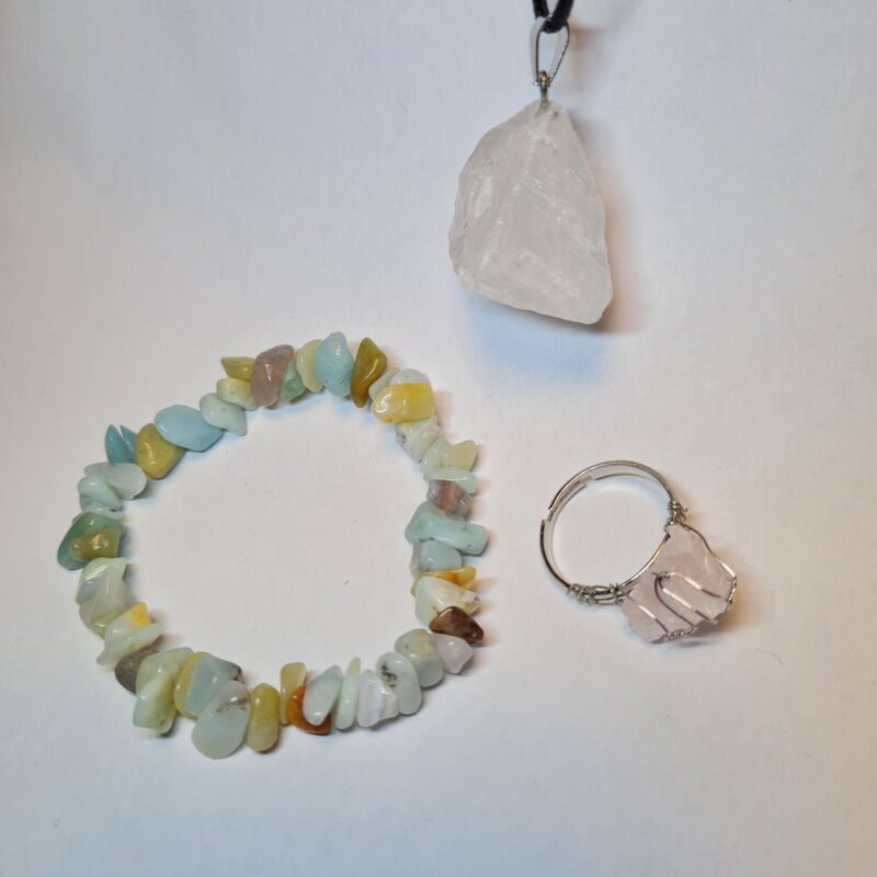 Set mit Amazonit Armband, Bergkristall Anhänger und Rosenquarz Ring auf weißem Hintergrund