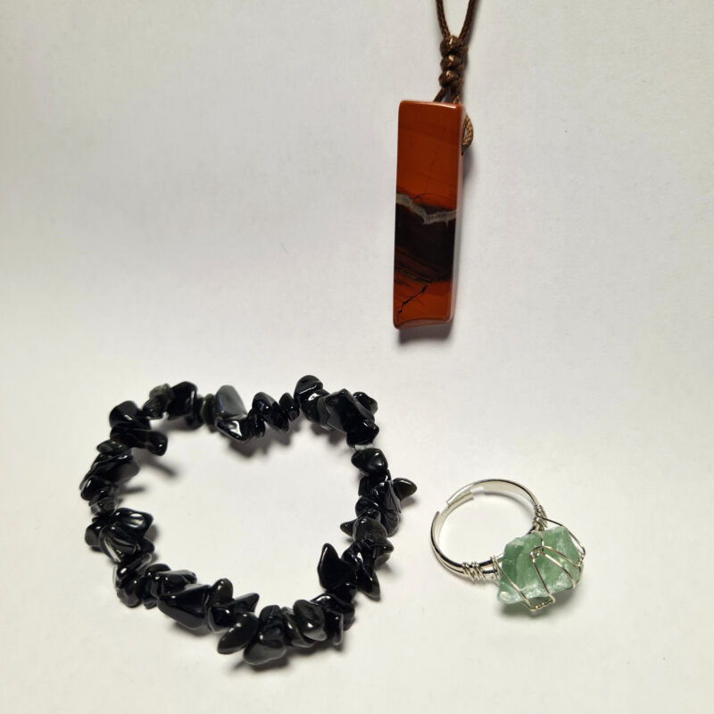 Set mit Obsidian Armband, rotem Jaspis Anhänger und fluorit Ring auf weißem Hintergrund